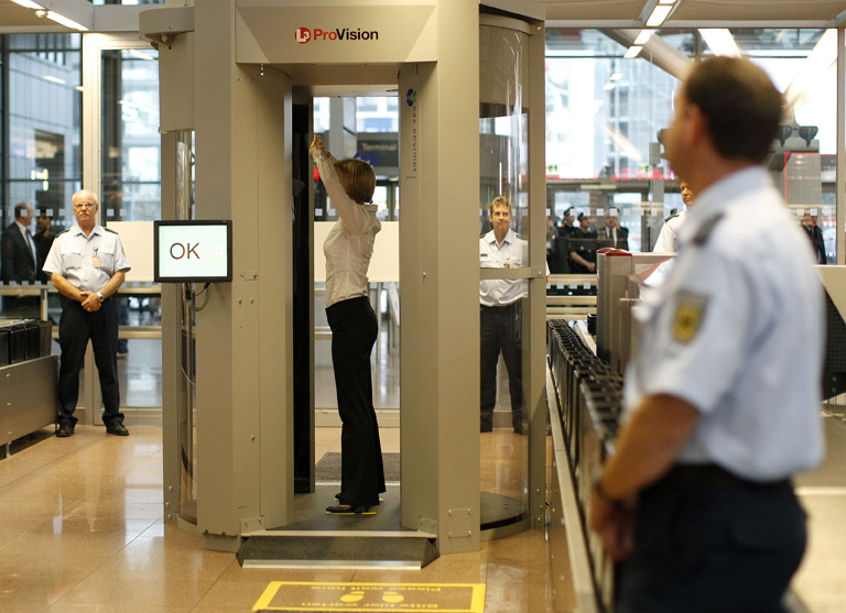 A security official demonstrates a full body scanner during a photocall at Departure Gate 2 at Hamburg Airport September 27, 2010. Germany started on Monday the voluntary use of two 'L-3 Provision ATD' body scanners for a test period over the next six months at the airport. REUTERS/Christian Charisius (GERMANY - Tags: TRANSPORT SCI TECH)